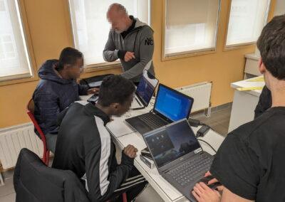 Élèves naviguant sur des pc portables avec un professeur