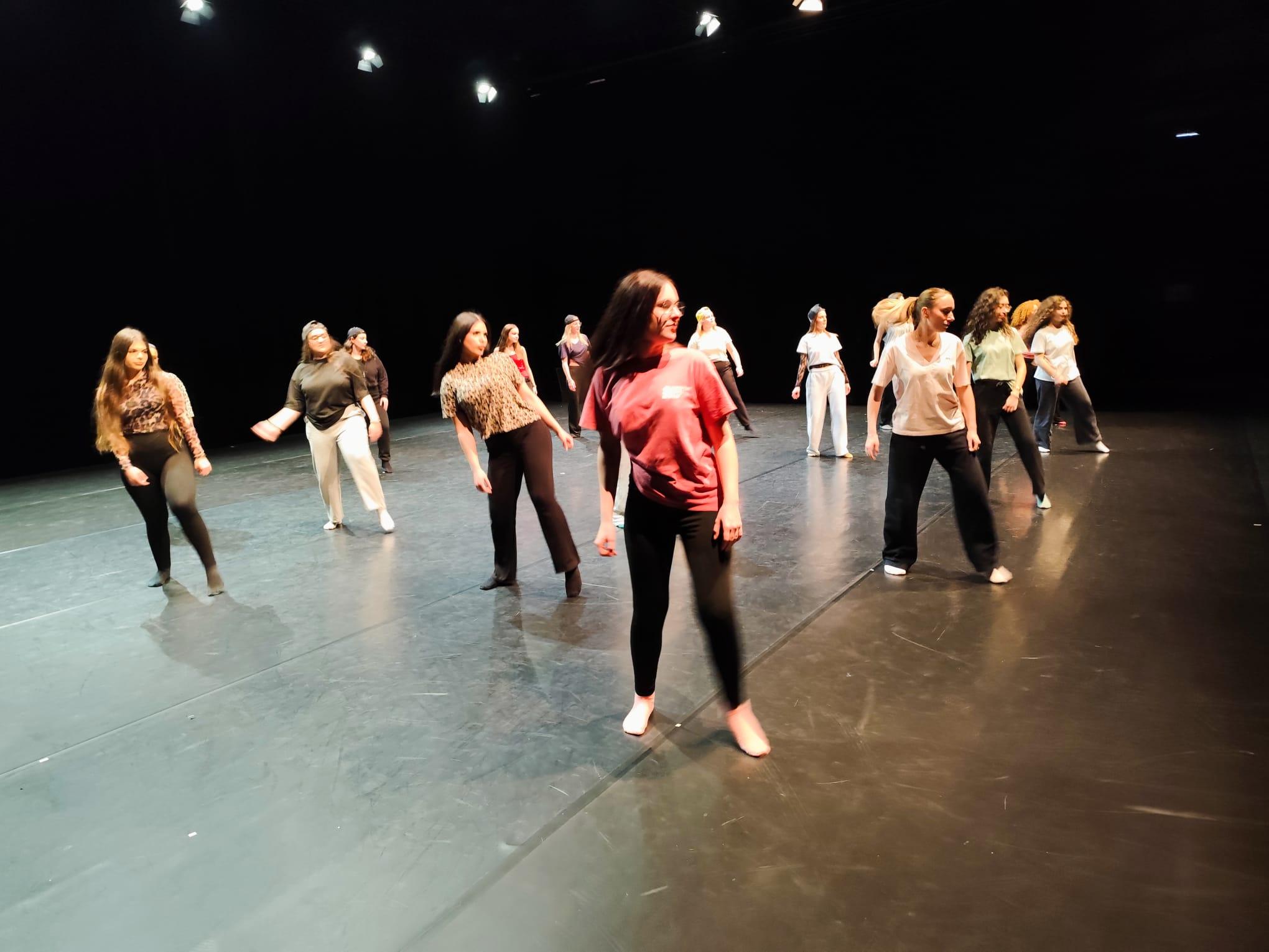 Les danseuses, réparties sur quatre lignes, dansent, penchées en arrière. 